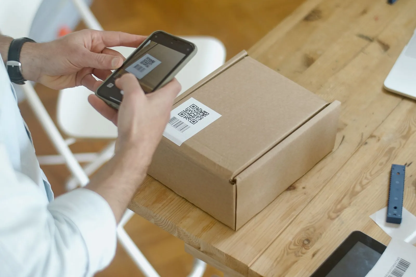 Hands scanning a QR code label with a smartphone on a wooden table