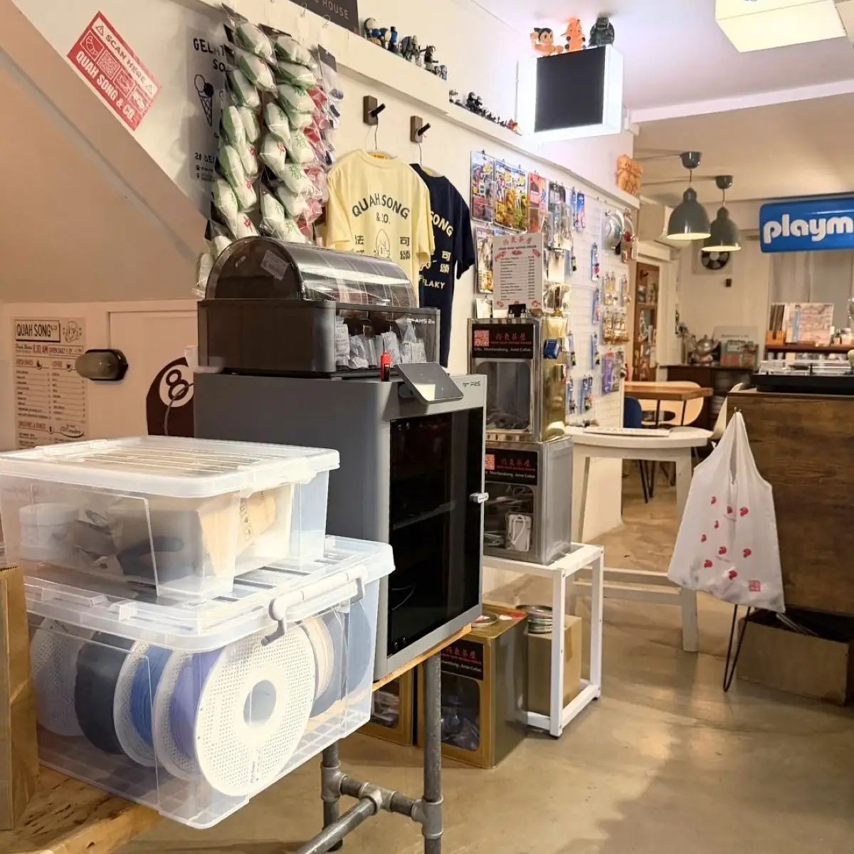 A Studio Node workspace at Quah Song & Co. — 3D printer with AMS, neatly organised filament storage, and shelves of finished products